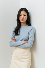 Obraz premium Woman In Light Blue Long Sleeve Shirt And Cream Skirt Standing In Clean Studio Portrait