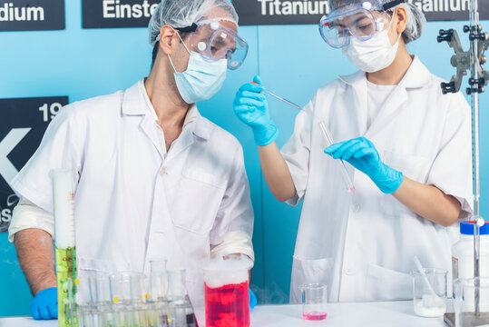 Scientist man woman working together team partner look into Microscope research in science laboratory. Two Asian scientist use microbiology microscope chemistry lab equipment. Biochemistry researcher