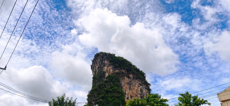 Scenic view of a majestic limestone mountain peak under a vibrant blue sky with fluffy white clouds, natural landscape copy space.