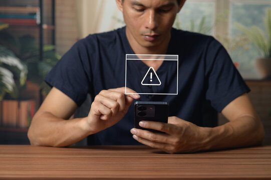 Young Man Using Smartphone with Security Alert Overlay at Home Office