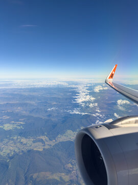 QUEENSLAND AUSTRALIA - MARCH 3 2025: A Jetstar plane with wing tips flying over  mountains in rural Queensland Australia with clear blue skies