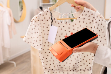 Person holding polka dot blouse and payment terminal © Pixel-Shot