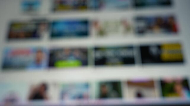 Blurred web page with rows of thumbnail images on a screen moving, suggesting browsing media selection and online content