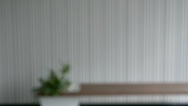 Abstract blurry backdrop of a minimalist cozy room or office interior with green plant out of focus. Blurred background plate for virtual meeting zoom background, green screen vfx and copy space