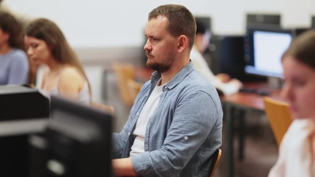 Adult man using computer for work in coworking space with team