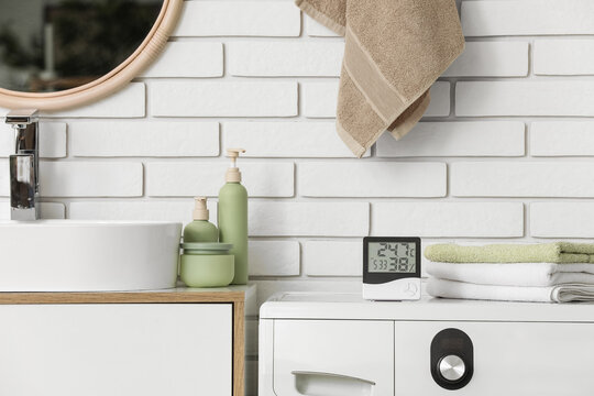 Modern bathroom sink with towels and digital hygrometer