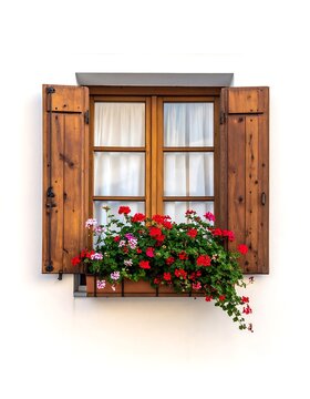 A wooden window with shutters and a vibrant flower box