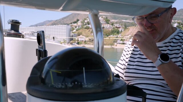 Mature skipper navigating sailboat with compass