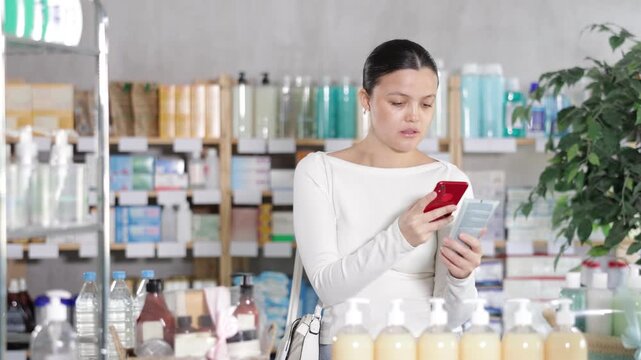 Female customer using phone to check ingredients of body lotion