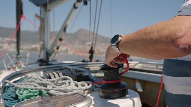 Sailor's hands working with rope on sailboat winch