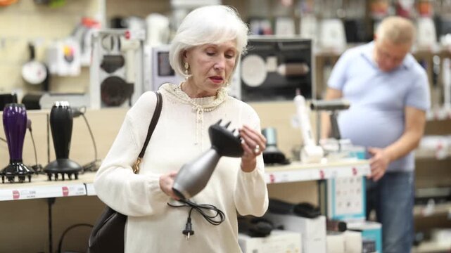 Mature woman choose hair dryer at a hardware store. High quality 4k footage