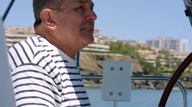 Senior man steering a sailboat at sea