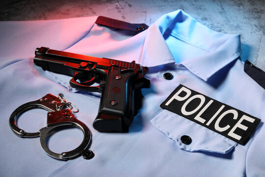 Police uniform with handgun and handcuffs on concrete surface