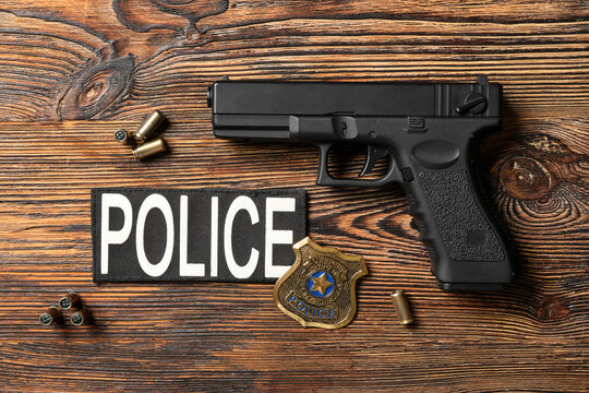 Police handgun with badge and ammunition on wooden surface