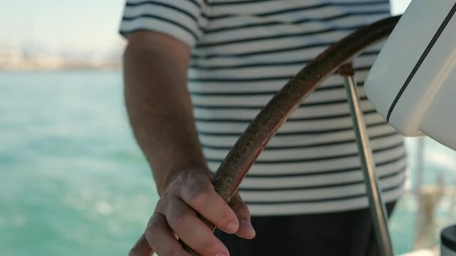 Sailor hands steering a yacht on the open sea