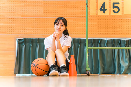 A female student cheering on her school club, the basketball team, at a sports festival, class match, tournament, or game.