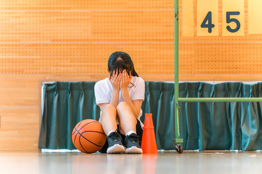 A female student crying while cheering for her school club, the basketball team, at a sports festival, class match, tournament, game, losing, retirement.