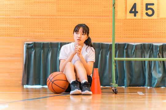 A female student cheering on her school club, the basketball team, at a sports festival, class match, tournament, or game.