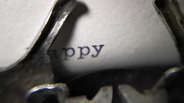Close up macro shot of an antique typewriter spelling out Happy Anniversary on white paper.