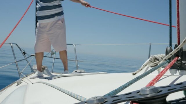 Sailor walking on the bow of a sailboat during a regatta