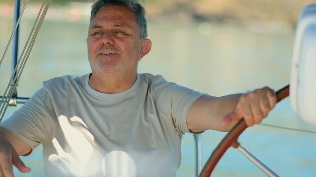Mature skipper steering sailboat at sea