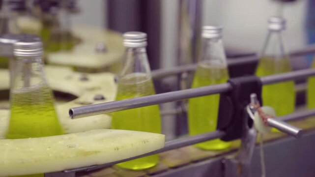 Glass bottles filled with juice moving on automated factory conveyor line
