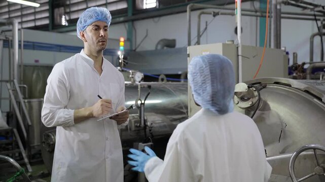 Food industry engineers examining large sterilization tank equipment in plant