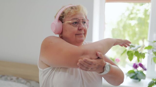 Senior lady doing cross body shoulder stretch during home fitness fitness at home