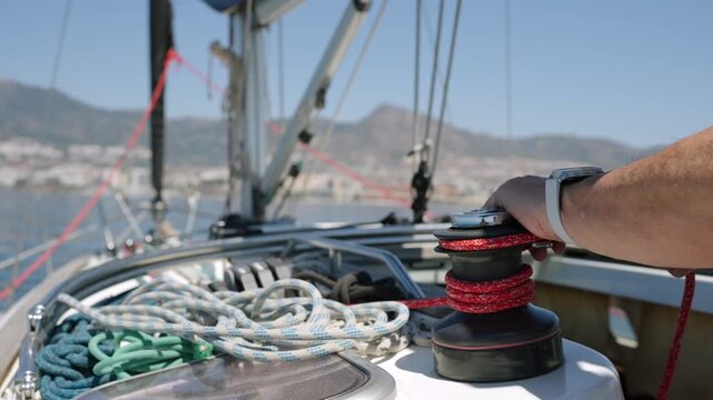 Sailor's hands working with rope on a winch of a sailing boat