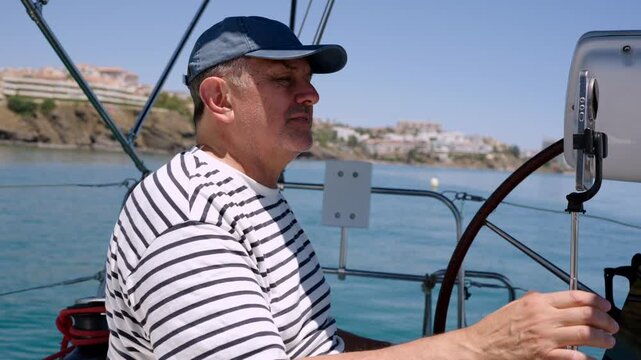 Experienced male skipper steering sailboat at sea