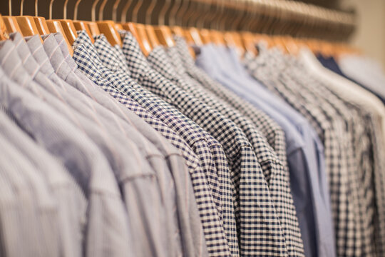 Men's dress shirts hanging on wooden hangers in clothing store