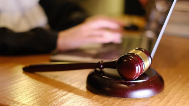 Judge typing on laptop computer with gavel on desk