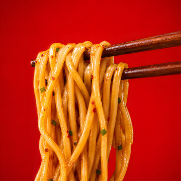 Spicy Noodles Held with Chopsticks on Red Background