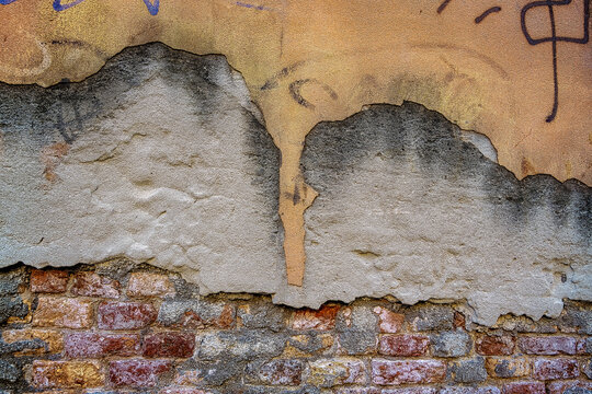 Plaster falling off of an old brick wall. Old cracked and ruined wall made of red bricks with remains of plaster in Venice, Italy