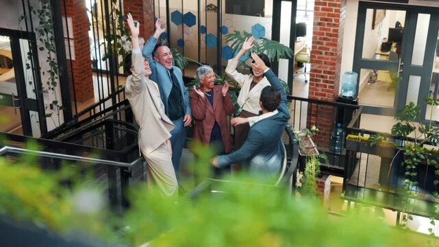 Team, lobby and business people with hand stack, applause and success for remodeling contract. Green office, above and workers on stairs, achievement and celebrate news at interior design agency