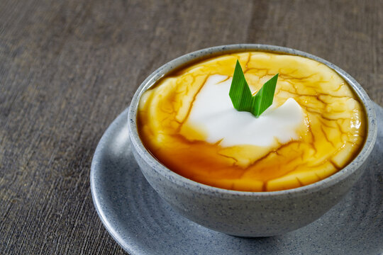 bubur sumsum, Indonesia&rsquo;s creamy coconut rice porridge served in a grey bowl with palm sugar syrup and fresh green pandan leaf