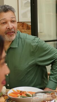 Vertical video: Hearing voice green-shirt man turning smiling watching during home meal with roast