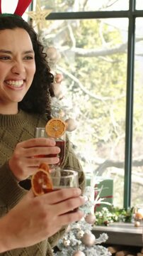 Vertical video: Laughing lady in jumper with orange drink by tree, man coming to toast, copy space