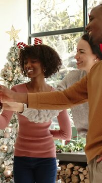 Vertical video: Reaching right Santa-hat man starting holiday toast by tree, guests raising glasses