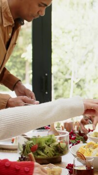 Vertical video: Passing plates, diners at table as roast arriving, green-shirt carving for serving