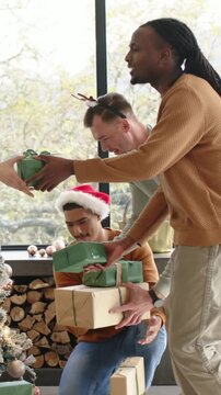 Vertical video: Leaning 3 men in hats passing placing green boxes under tree at home, copy space