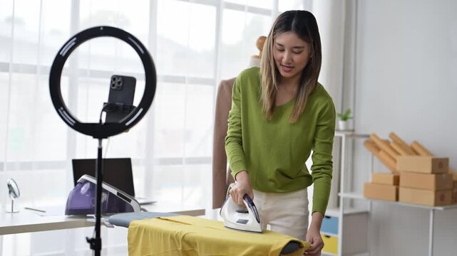 Young asian woman ironing clothes and recording a video tutorial