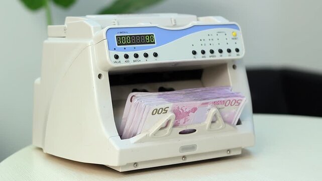 Cashier Inserting and Removing Euro Banknotes From Money Counter Machine. This footage conceptually represents financial transactions, commercial banking, cash flow management in the European economy
