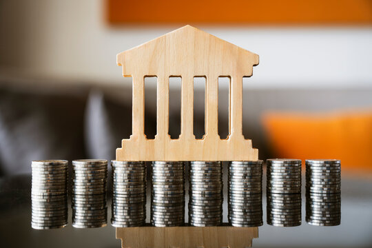 Bank wooden model on stacked coins for dollar cost averaging DCA investment plan concept, long term financial savings asset management, banking foundation stability, capital growth analysis.