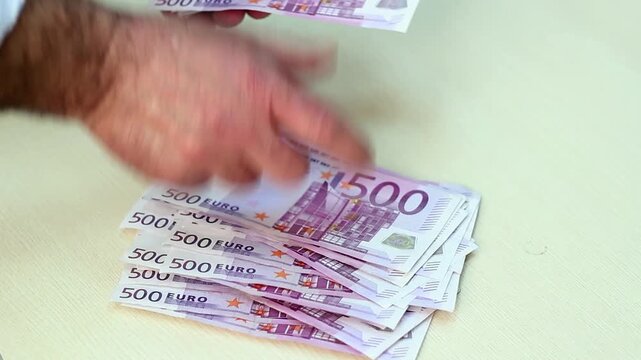 Man Counting Life Savings in 500 Euro Banknotes Financial Security Concept. Themes of personal wealth accumulation, cash savings, banking deposits, cash flow management and European financial security