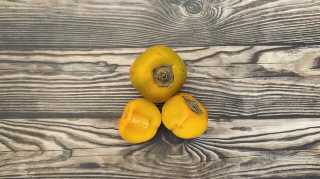 A fresh persimmon or Diospyros kaki on a wooden table
