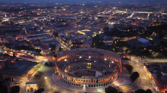Rome, Italy. Aerial night 4K panoramic drone view of the city at dusk. Majestic view of the ancient city skyline with Basilics, Coliseum, ancient ruins, iconic buildings. Europe from above.