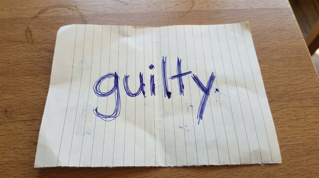 Handwritten Word Guilt on Crumpled Paper Background Displayed.