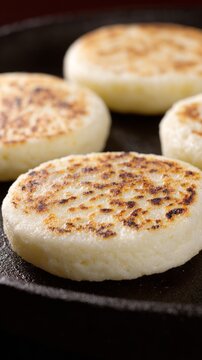 Arepas on cast-iron griddle beside cuatro guitar, tropical culinary and music scene.
