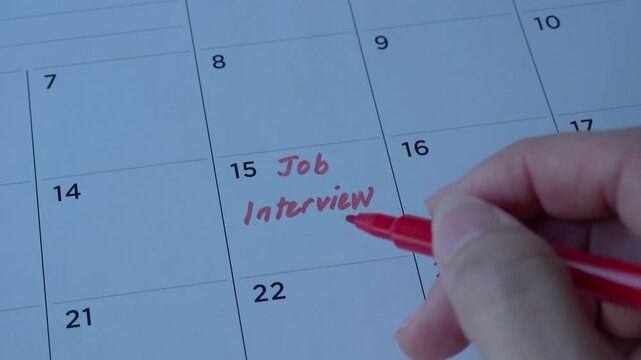 Job interview text in red, written on desk calendar. Employment or careers concept.